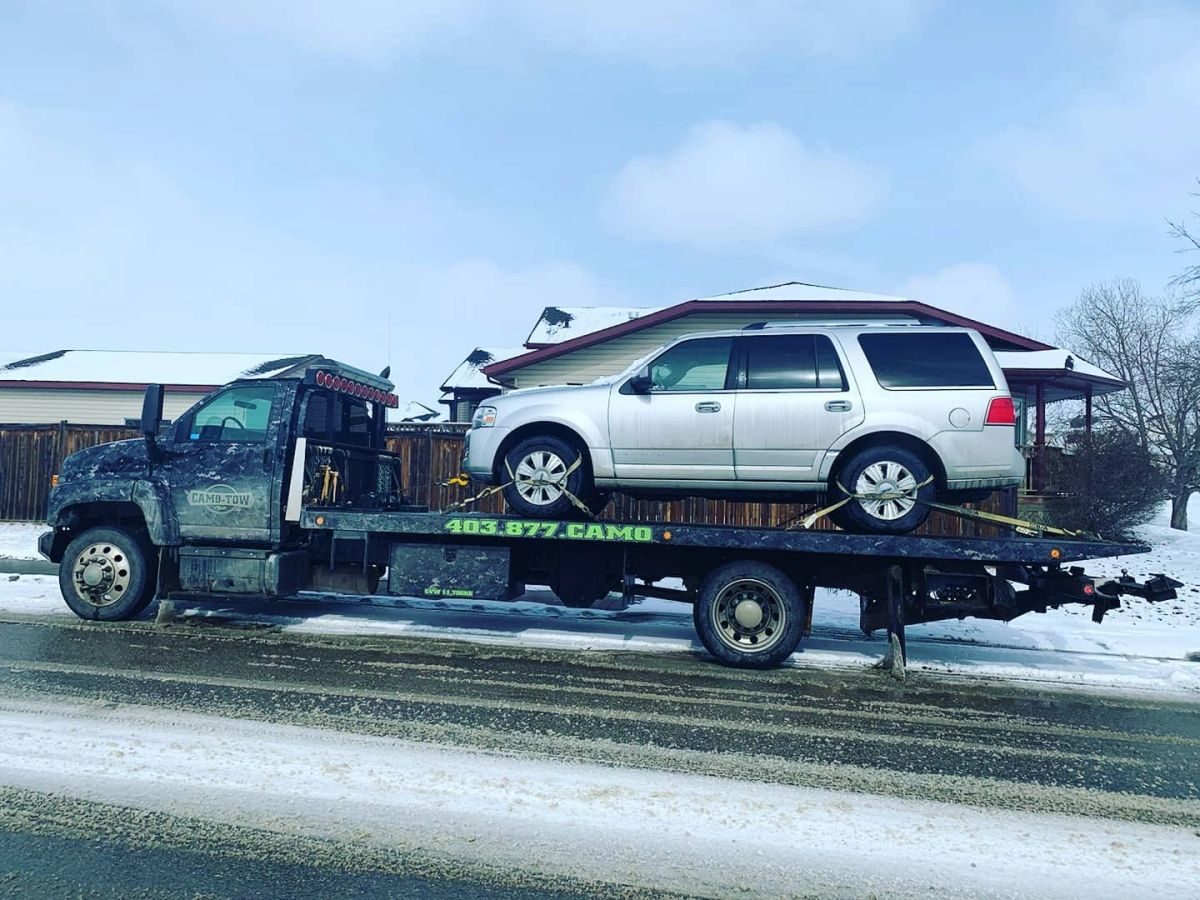 Camo Tow flatbed hauling an SUV