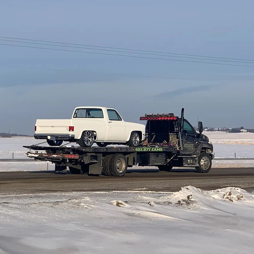Camo Tow flatbed with a white pickup in the snow